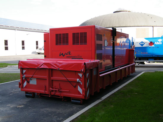 Stromaggregat TYP WA-DG 670 "S" mit einer Leistung von 670 kVA im Aggregatcontainer in Feuerwehr Ausr&uuml;stung, aufgebaut auf einen Abrollunterbau mit elektrischer Kabeltrommel zur Aufnahme von 25 Metern Kabel in H07-RNF